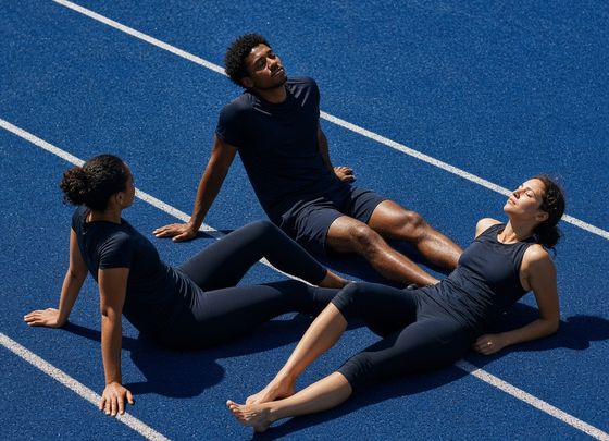 Three runners resting on a blue track